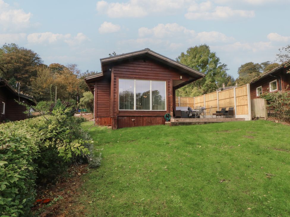 A cabin with a deck and grass area at Woodlands View in Leek