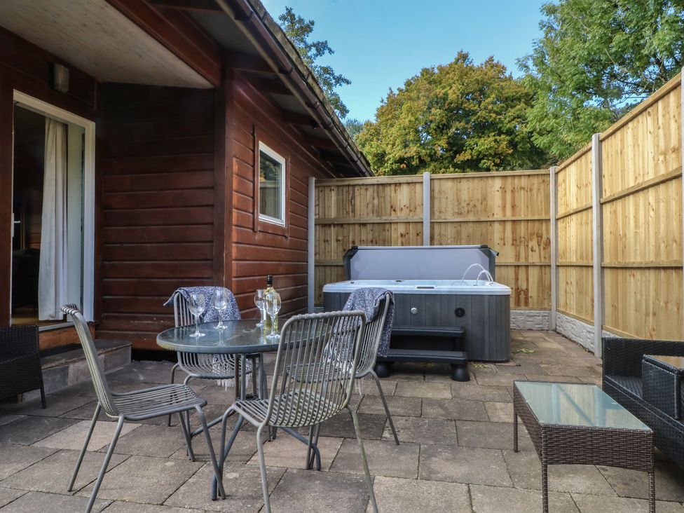 An outdoor seating area with chairs and a hot tub at Woodlands View in Leek