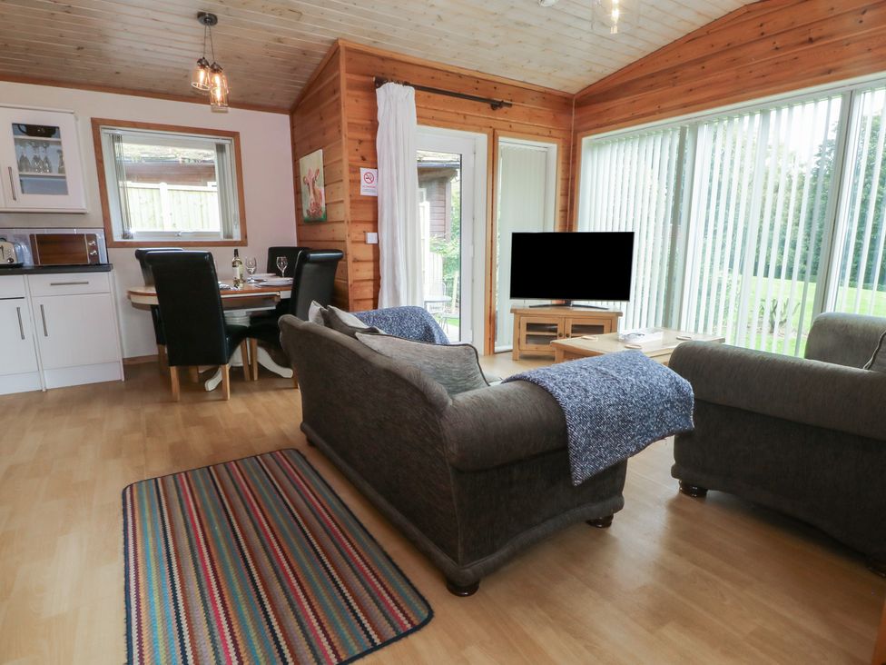 A living room with a sofa and dining table at Woodlands View in Leek