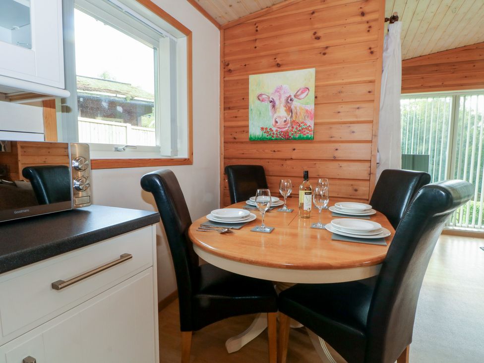 A dining room with a round table and chairs at Woodlands View in Leek
