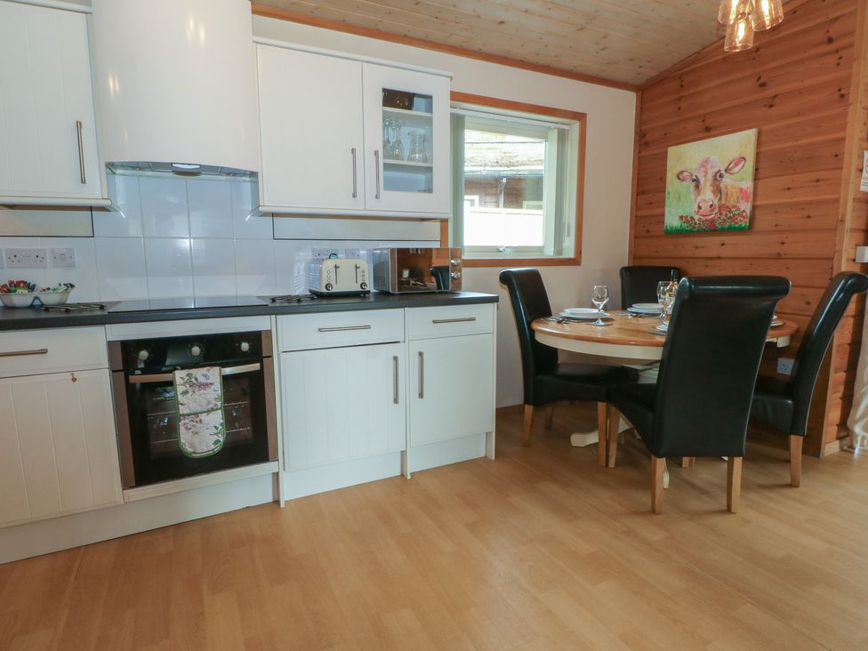 A kitchen with white units and a dining table at Woodlands View in Leek