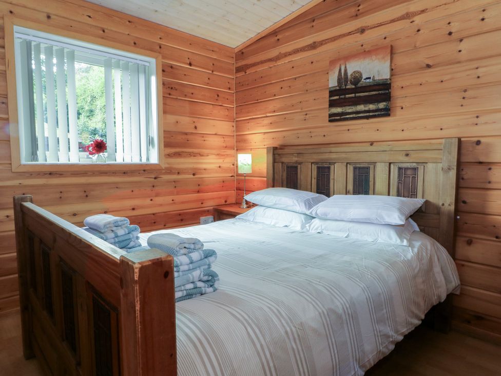 A bedroom with a wooden bed and lamp at Woodlands View, Leek