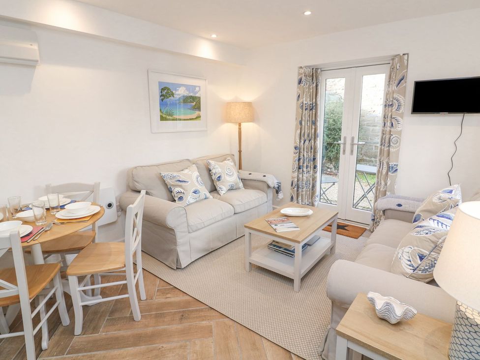 A living room with a sofa and dining table at Quay cottage Salcombe