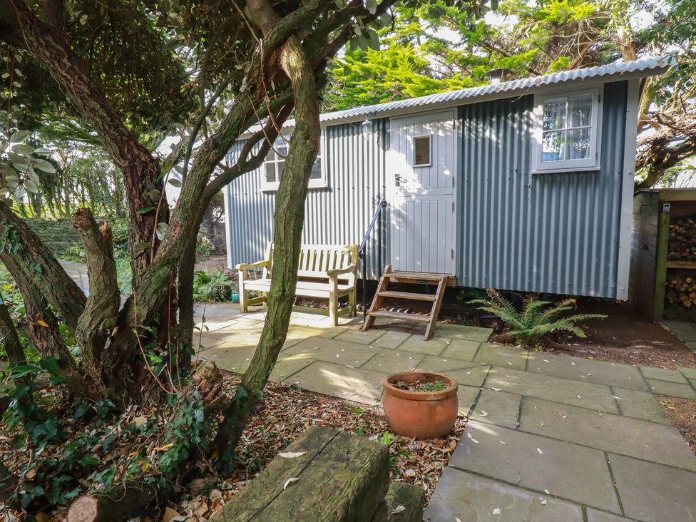 A shepherd hut with a bench and steps in a garden at Hillbre Shepherd Hut in Padstow