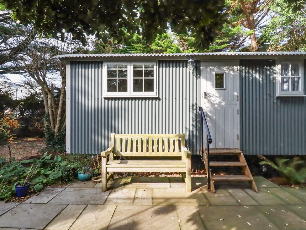 A shepherd hut with a wooden bench and plants at Hillbre Shepherd Hut in Padstow