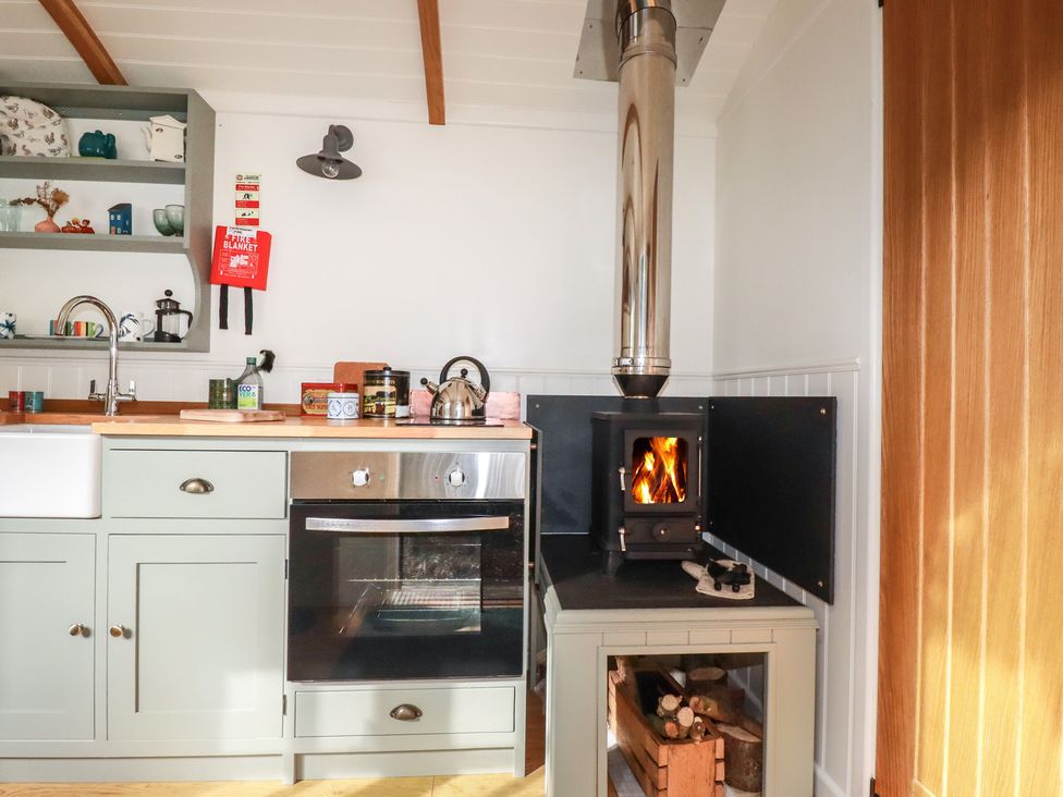 A kitchen with a sink, stove, and wood stove at Hillbre Shepherd Hut in Padstow