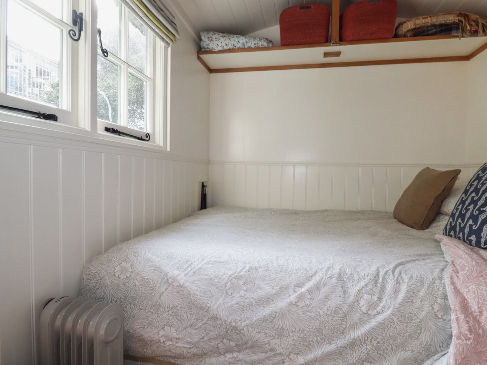 A bedroom with a bed and shelves at Hillbre Shepherd Hut in Padstow