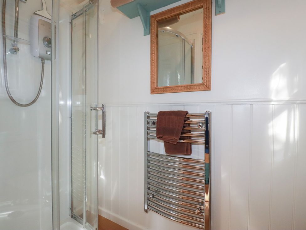 A bathroom with a glass shower and a towel rail at Hillbre Shepherd Hut in Padstow