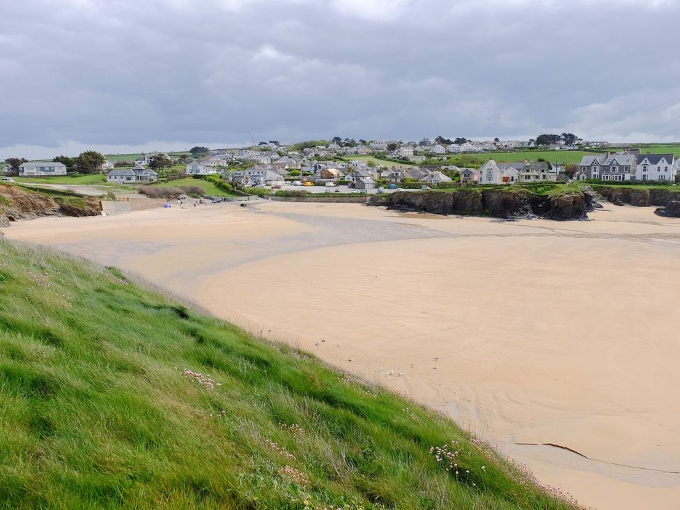 A beach with sand and grass along with distant houses at Hillbre Shepherd Hut Padstow
