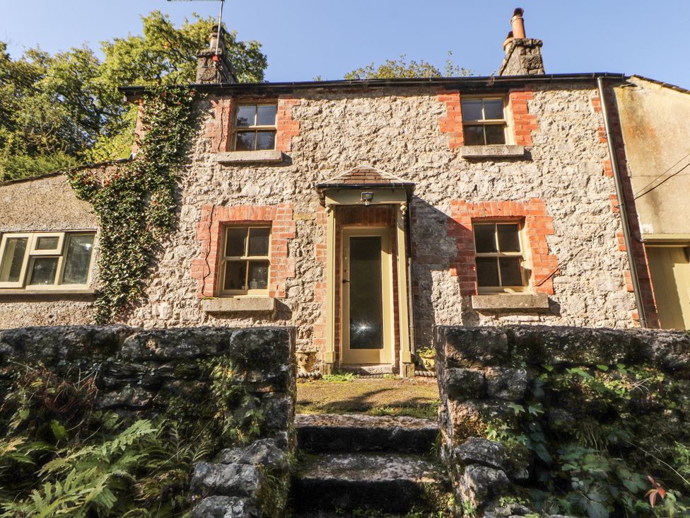 A house with stone walls and a front door at Rock Cottage in Milnthorpe
