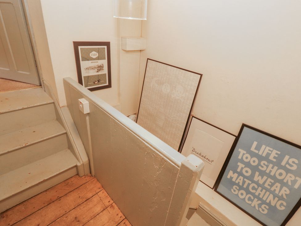A staircase with framed pictures and a light fixture at Rock Cottage in Milnthorpe