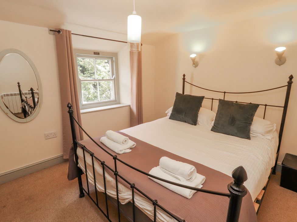 A bedroom with a bed, pillows, and a window at Rock Cottage in Milnthorpe