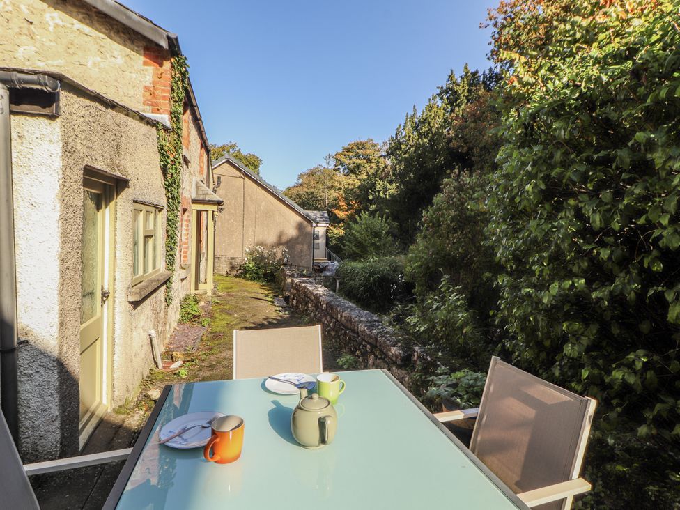 An outdoor seating area with a table and mugs at Rock Cottage in Milnthorpe