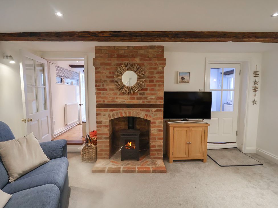 A living room with a fireplace and television at Nutshell in Aldeburgh
