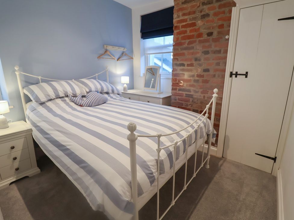 A bedroom with a bed and dresser at Nutshell in Aldeburgh