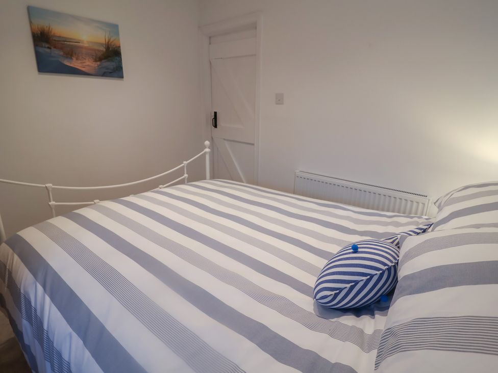 A bedroom with a bed and blue striped pillow at Nutshell in Aldeburgh