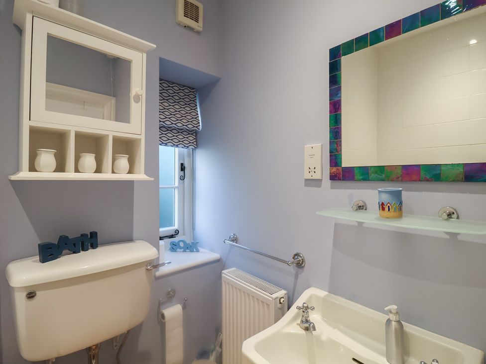 A bathroom with a toilet, sink, and shelf at Nutshell in Aldeburgh