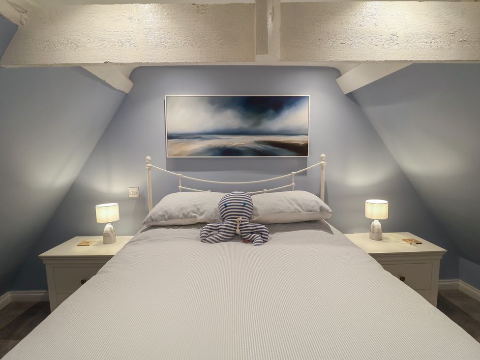 A bedroom with a bed and nightstands at Nutshell in Aldeburgh