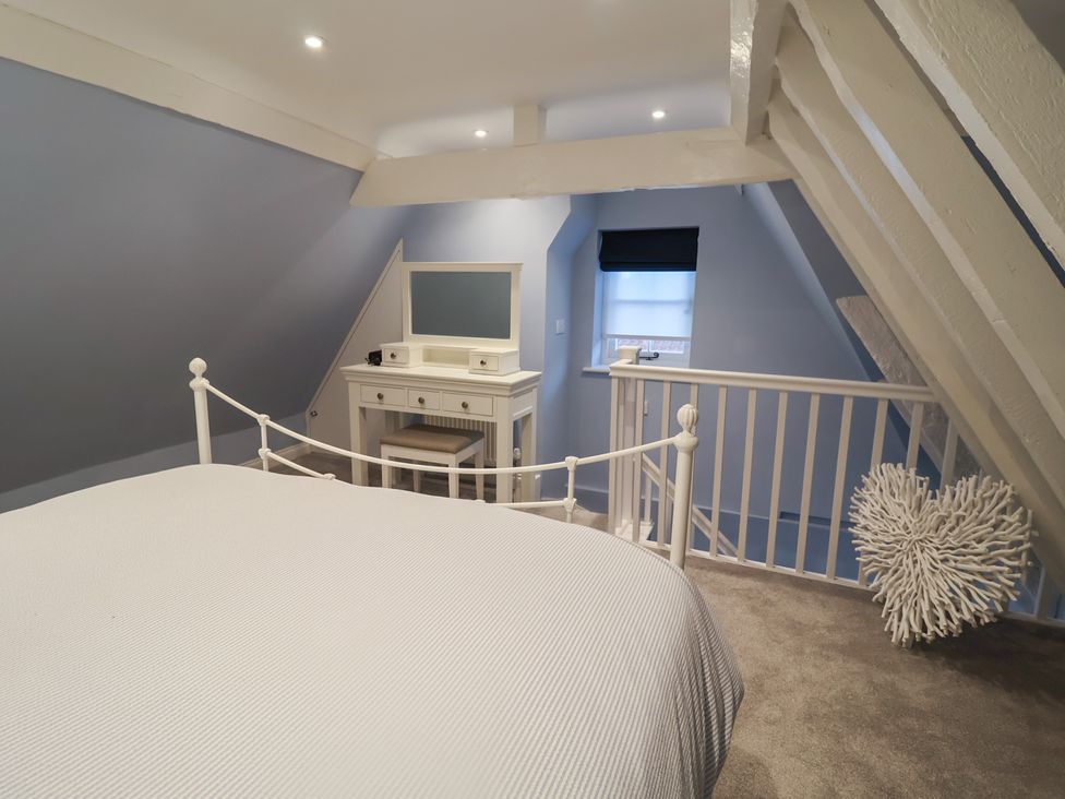 A bedroom with a bed and vanity at Nutshell in Aldeburgh