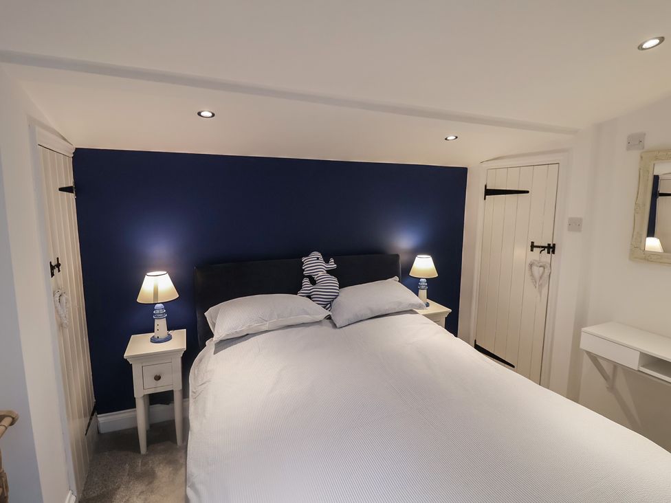 A bedroom with a bed and bedside table at Nutshell in Aldeburgh
