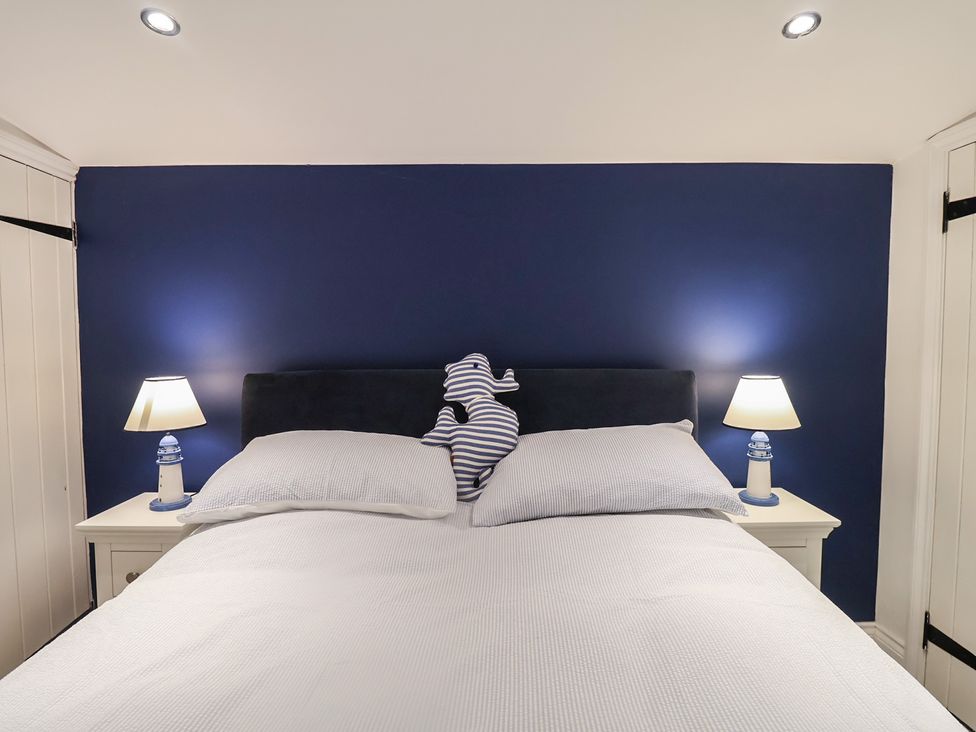 A bedroom with a blue wall and a bed at Nutshell in Aldeburgh