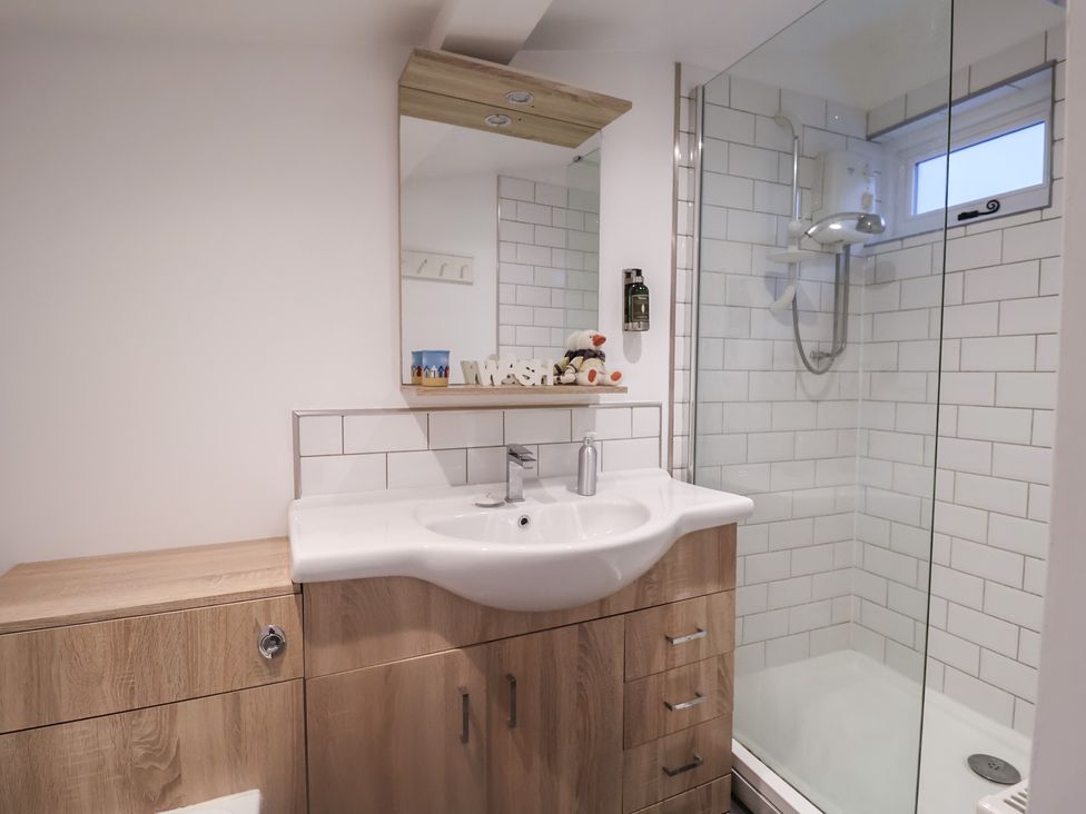 A bathroom with a sink, mirror and shower at Nutshell in Aldeburgh