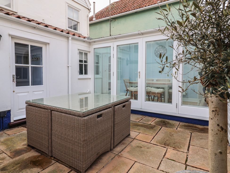A garden with a glass table and plants at The Nutshell in Aldeburgh