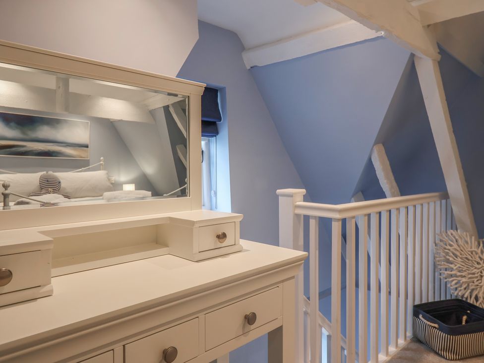 A bedroom with a dresser and a mirror at The Nutshell in Aldeburgh