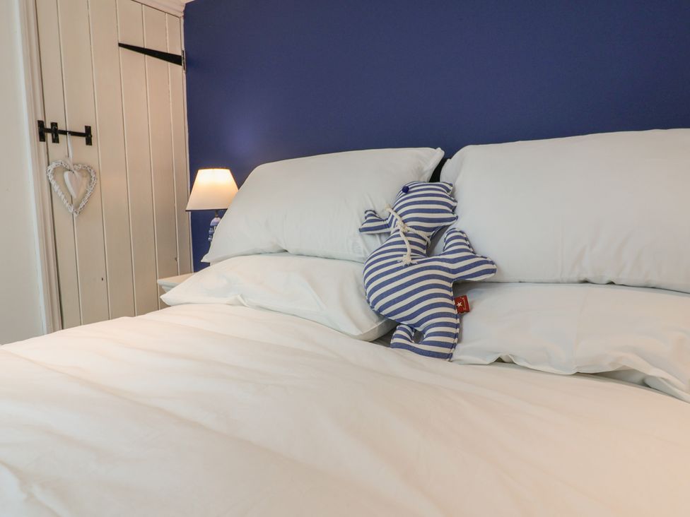A bedroom with a blue wall and a stuffed toy on a bed at The Nutshell in Aldeburgh