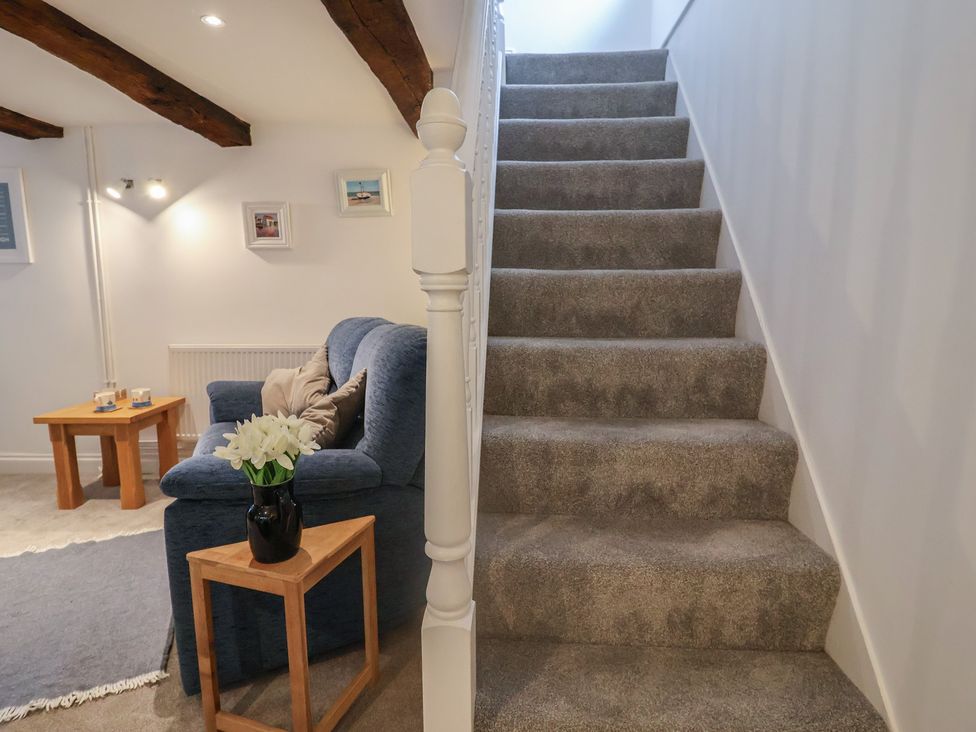 A living room with a blue sofa and stairs at The Nutshell in Aldeburgh