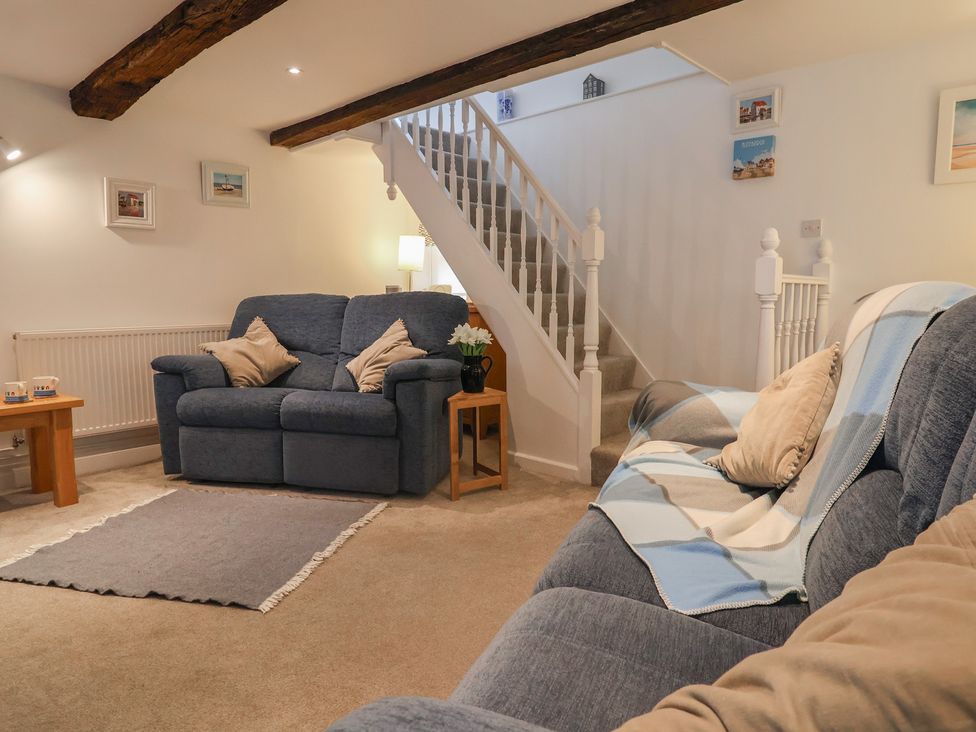 A living room with a sofa and staircase at The Nutshell in Aldeburgh