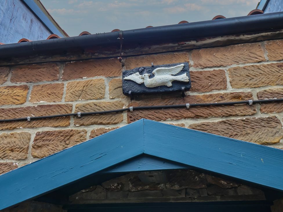 An ornamental plaque on a stone wall at Dove Cottage in Sneaton near Ruswarp