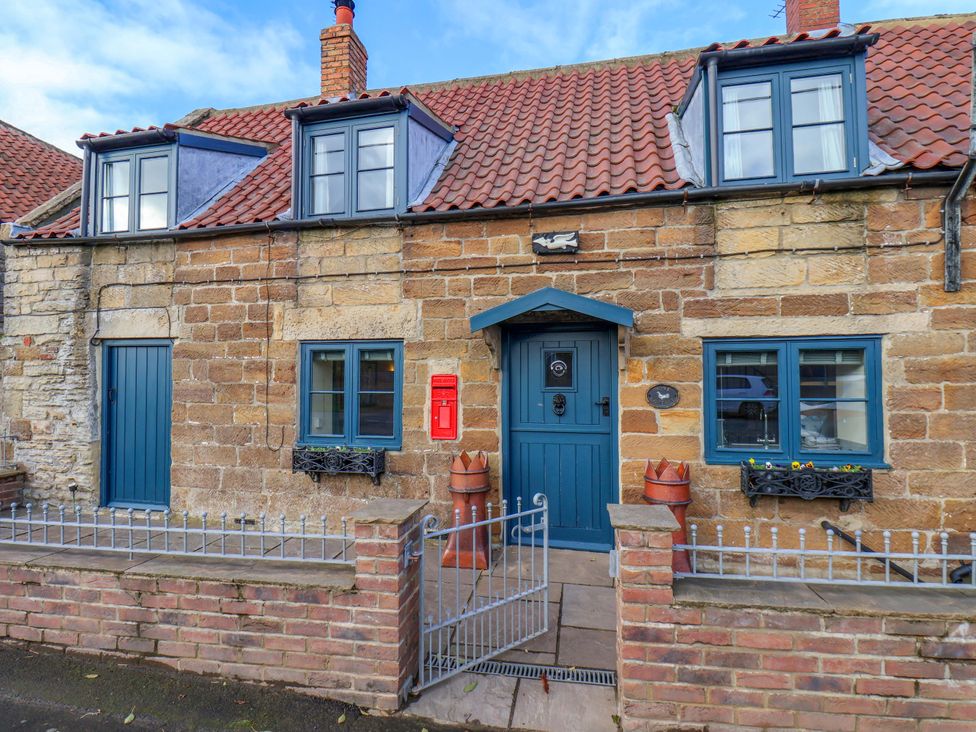 A house exterior with blue door and windows at Dove Cottage in Sneaton near Ruswarp