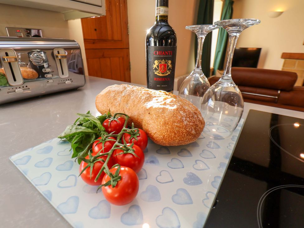 A kitchen featuring bread, tomatoes, a wine bottle with glasses at Dove Cottage Sneaton near Ruswarp