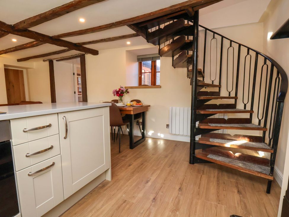 A kitchen with a spiral staircase and dining area at Dove Cottage in Sneaton near Ruswarp