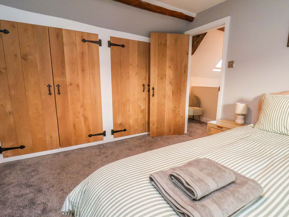 A bedroom with a bed and wardrobe doors at Dove Cottage Sneaton near Ruswarp