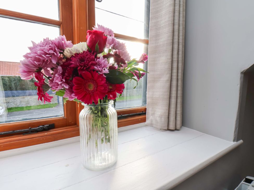 A vase of flowers on a windowsill at Dove Cottage in Sneaton near Ruswarp
