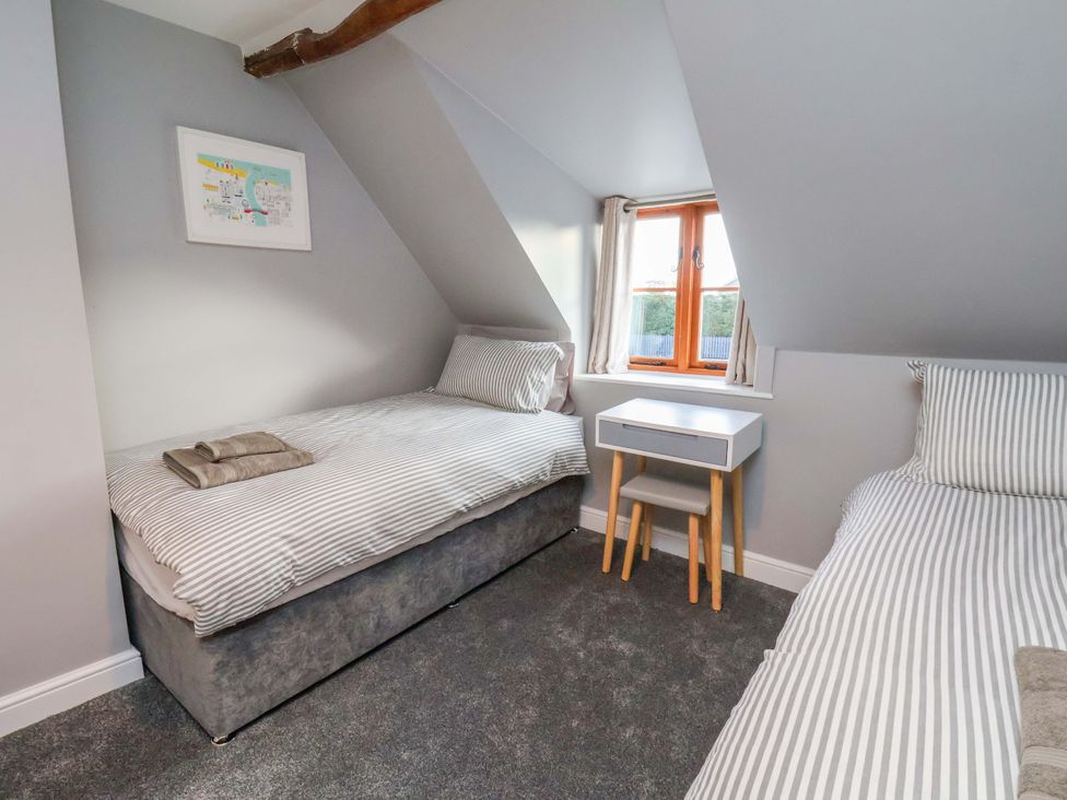 A bedroom with two single beds and a bedside table at Dove Cottage in Sneaton near Ruswarp
