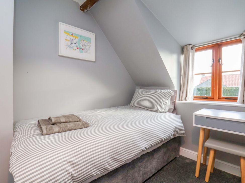 A bedroom with a bed and a desk at Dove Cottage Sneaton near Ruswarp