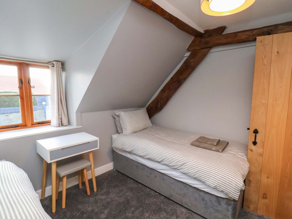 A bedroom with two single beds and a nightstand at Dove Cottage in Sneaton near Ruswarp