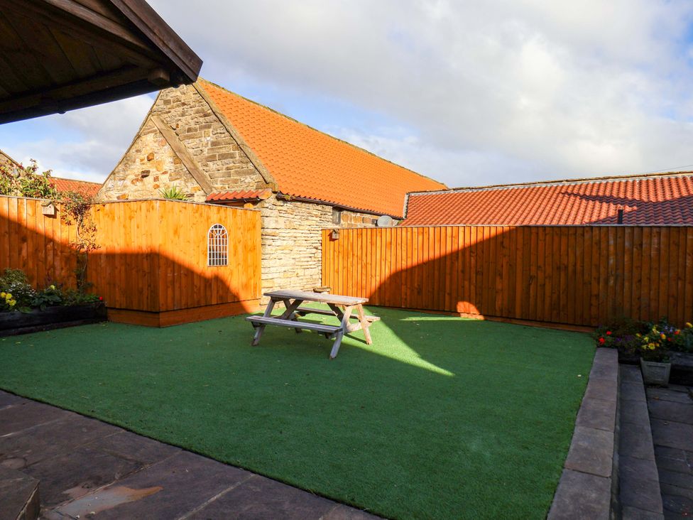 A garden with a picnic table and fence at Dove Cottage Sneaton near Ruswarp