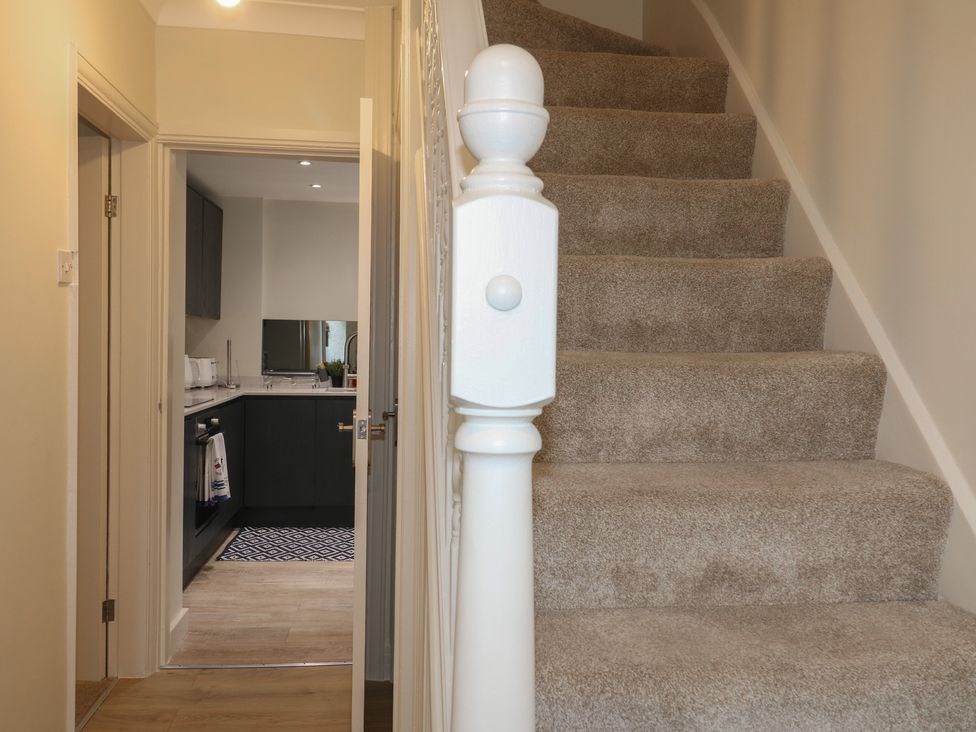 A hallway with stairs leading to an upper floor and a view into a kitchen at No.12 Alexandra Avenue Sutton-in-Ashfield
