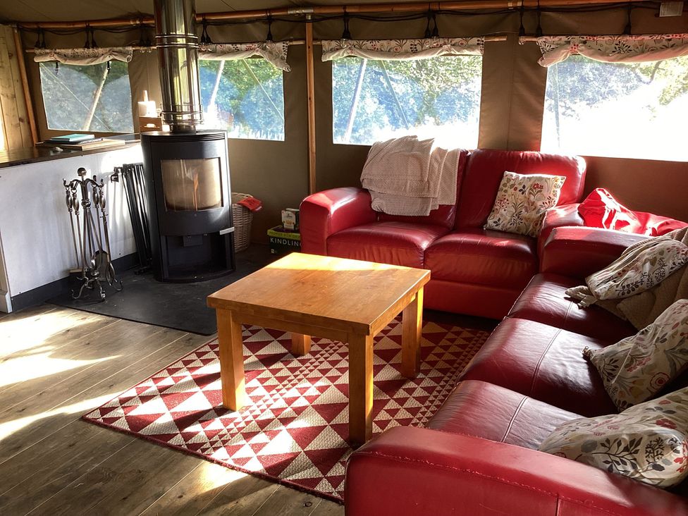 A living room with a wood stove and a red sofa at Camnant near Newcastle Emlyn