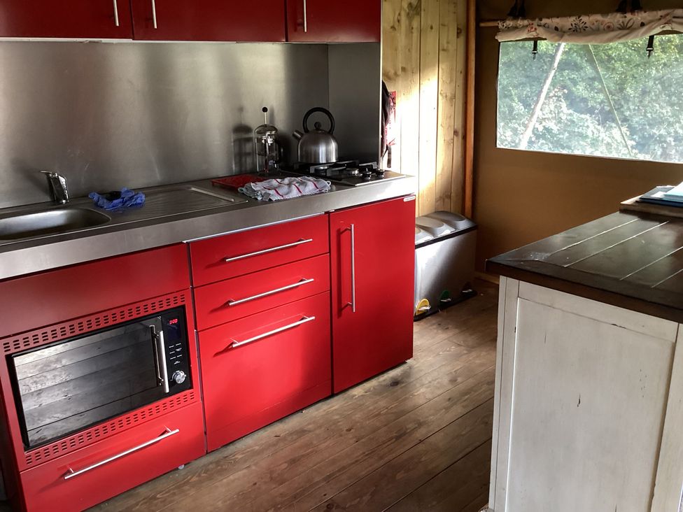 A kitchen with red cabinets and stainless steel appliances at Camnant near Newcastle Emlyn