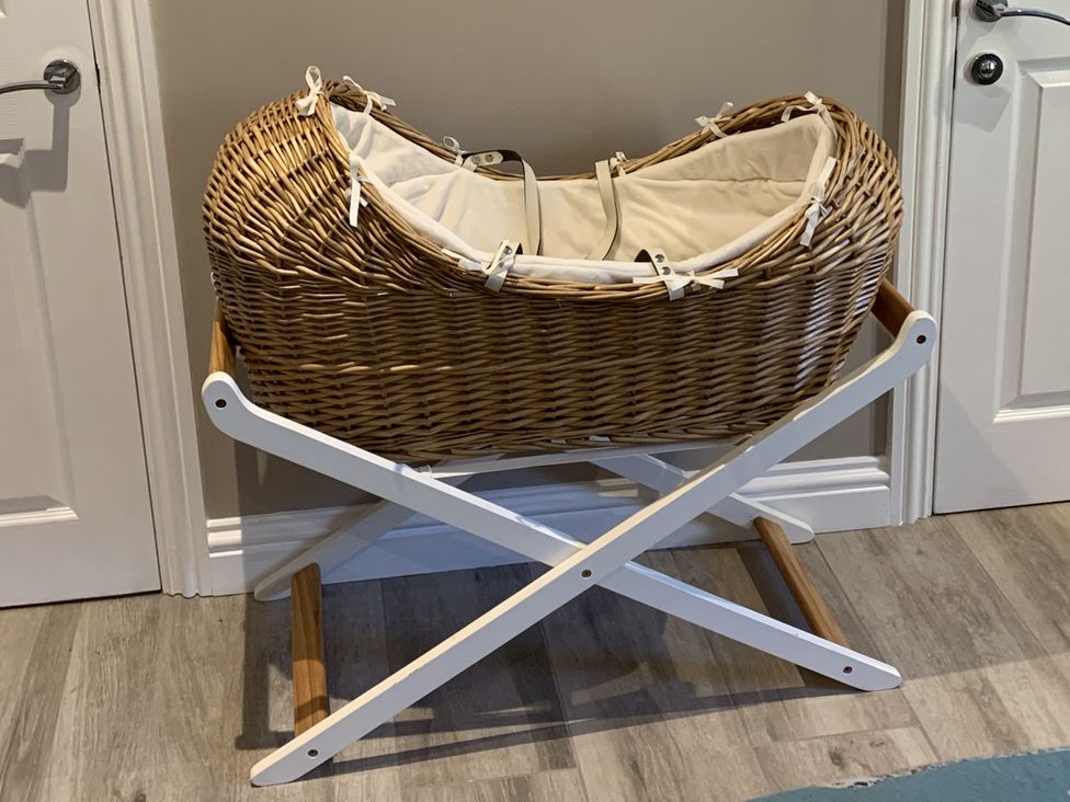 A moses basket on a stand in a nursery at Lily Stables Black Bourton near Bampton Oxfordshire