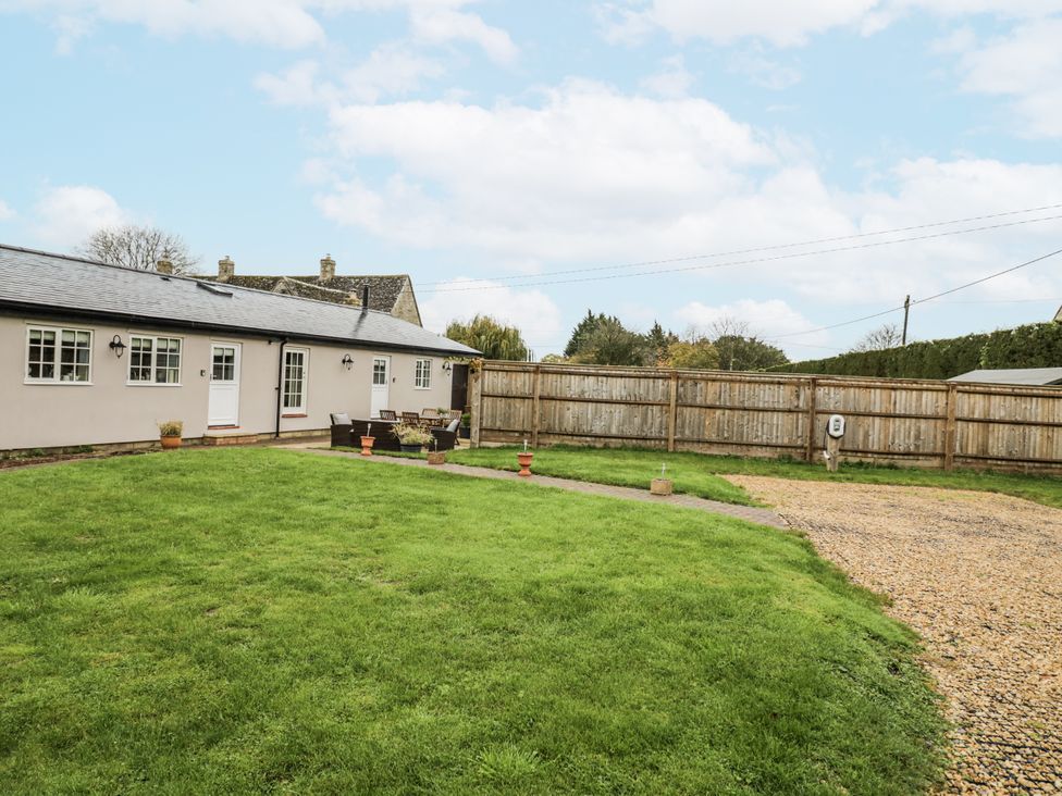 A garden with a seating area and grassy lawn at Lily Stables in Black Bourton near Bampton, Oxfordshire