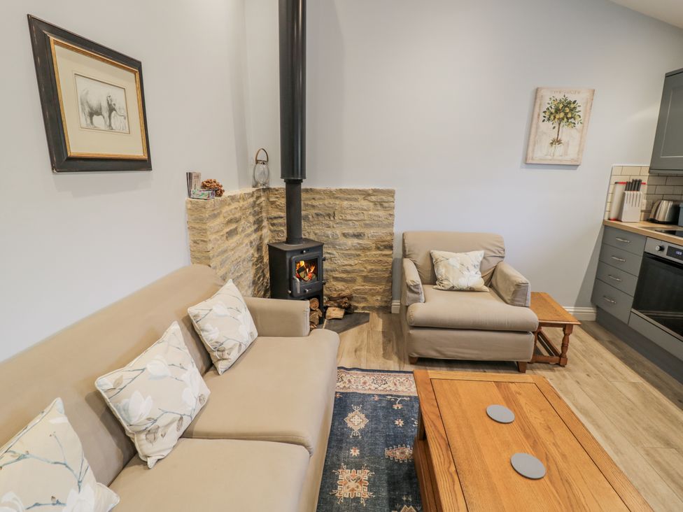 A living room with a sofa and armchair at Lily Stables in Black Bourton near Bampton, Oxfordshire