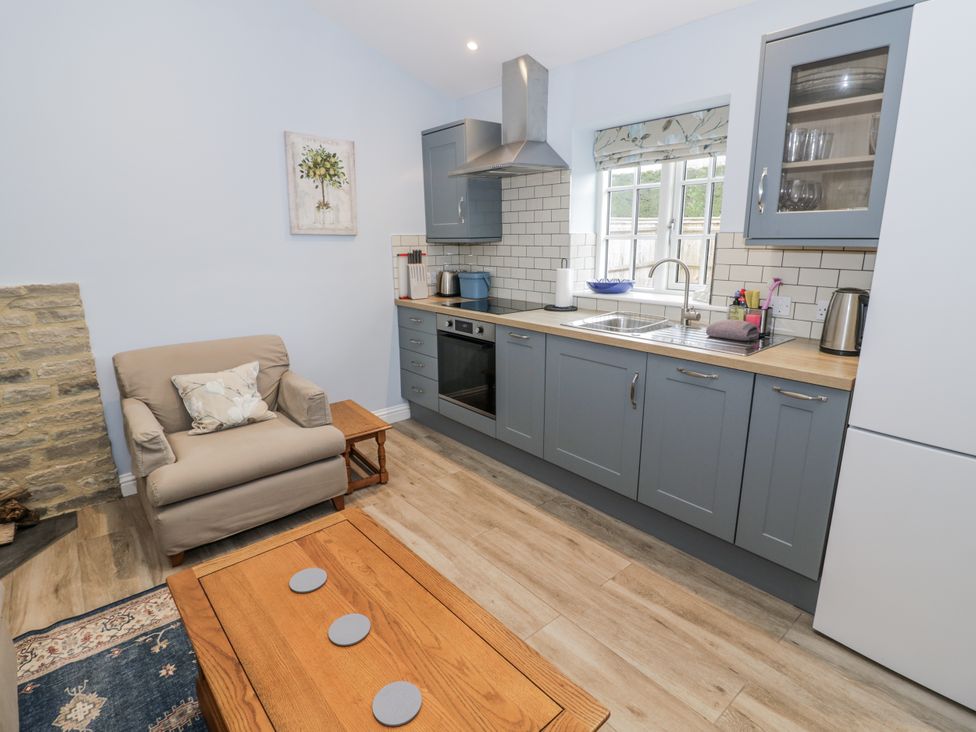 A kitchen with cabinets, oven, and sofa at Lily Stables in Black Bourton near Bampton, Oxfordshire