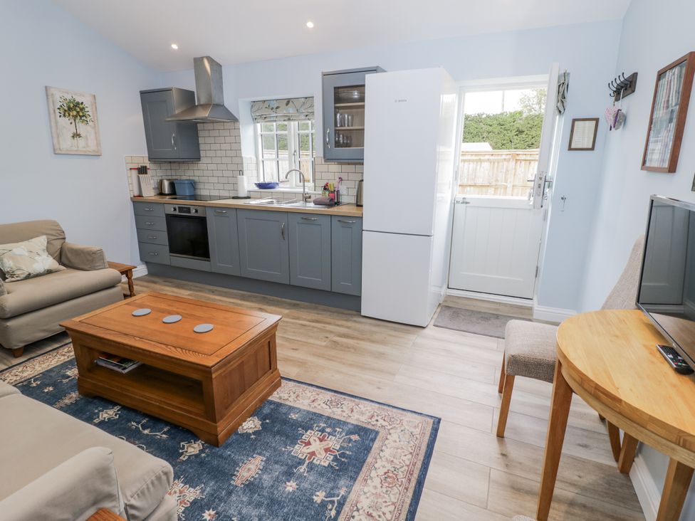 A kitchen with a refrigerator and sofa at Lily Stables in Black Bourton near Bampton, Oxfordshire