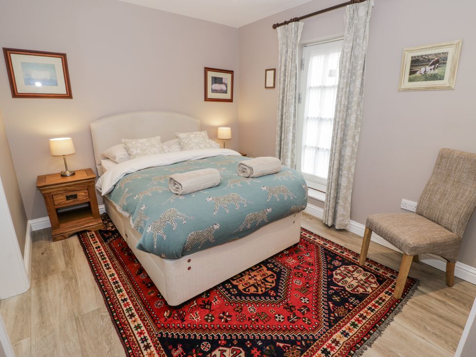 A bedroom featuring a bed with patterned bedding and a nightstand at Lily Stables Black Bourton near Bampton, Oxfordshire
